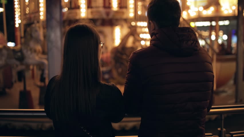 Young couple together looking to attraction in a night street