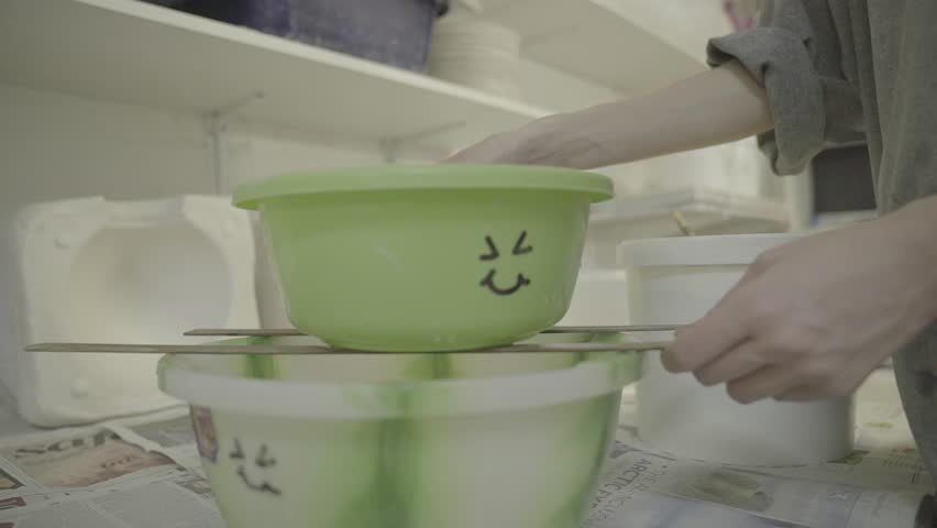 Ceramicist hands pouring glaze into buckets