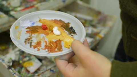Artist blends paints on a paper plate, close-up