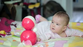 Small happy baby on the bed with red toy. Video full hd.