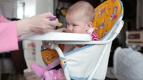 Mother feeds her little baby with a spoon. Video full hd.