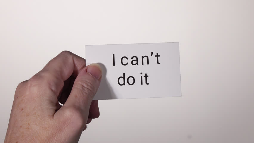 Model holding card in front of white background, then cutting card to change text from "I can't do it" to "I can do it". Royalty-Free Stock Footage #24725414