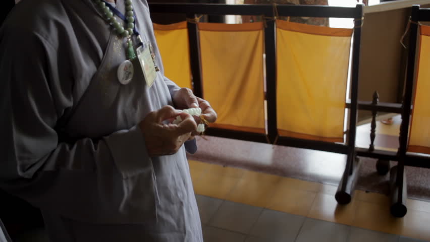Old man with prayer beads in the temple close-up