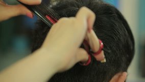 Barber cuts the hair of the client with scissors. Video full hd.