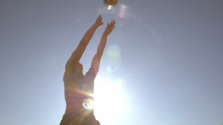 Low angle shot of young man jumping and passing a ball. Energetic guy playing volleyball while relaxing on the beach in the summer.