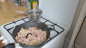 Wooden shovel stirs fried ham and mushrooms in a frying pan. Video full hd.