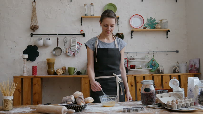 Happy beautiful woman preparing food in the kitchen and talking on mobile phone.