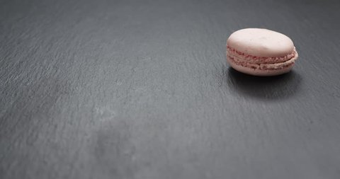 Slow motion of man hand bring pink macaroons on slate board, 4k 60fps prores footage