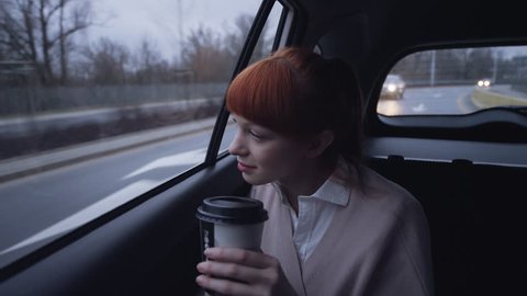 Woman in the Car Holding a Coffee Bin in her Hand