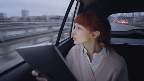 Woman Looking Through a Window and Using a Tablet
