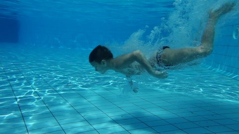 Boy in swimming pool swim underwater, slow motion