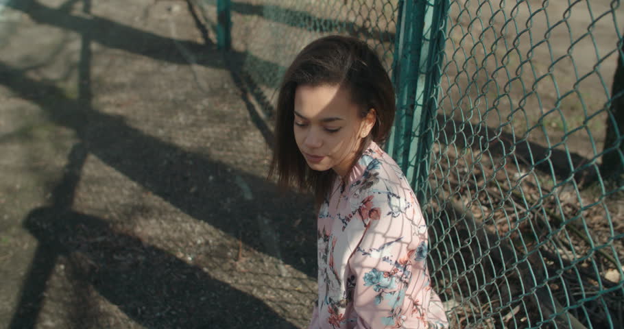 Portrait of young girl posing over metal fence, outdoors. 