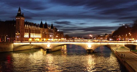 Parisian cityscape with traditional architecture, bridge, and the Seine river at night during blue hour with illuminated streets