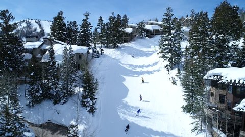 A beautiful aerial shot of people skiing in a snowy mountain ski resort in Deer Valley Park City Utah