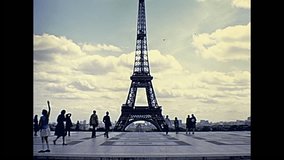 Paris Eiffel Tower panorama from Palais de Chaillot palace. Jardins du Trocadero gardens with tourists looking. Historic restored footage on 1976 in France. Parisians in vintage fashion clothing.