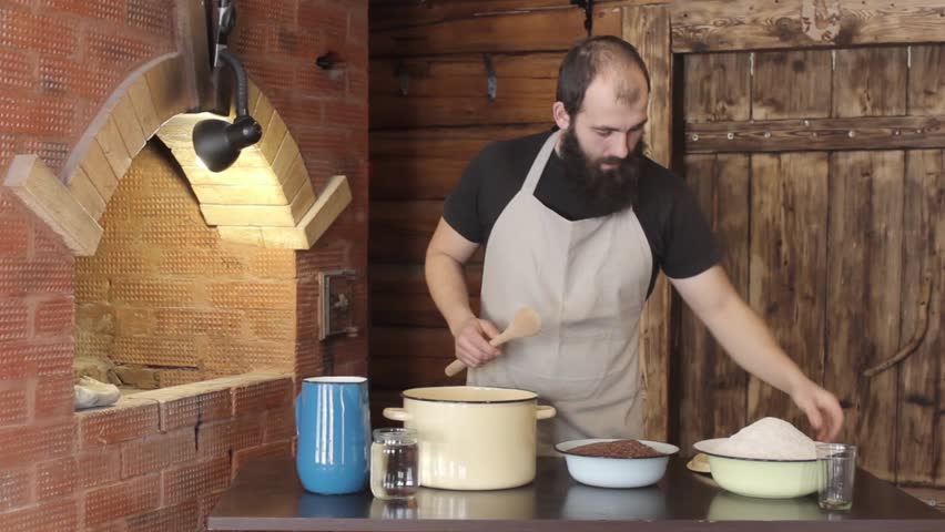 Male Baker pours into the pan the ingredients to kneading the dough