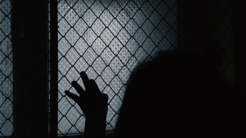 Helpless Child Shaking A Metal Fence Trying To Escape. Silhouette of scary young girl hands on the window fence. Refugees or abandoned child. Mental Institution. Family violence. Fingers on the fence Royalty-Free Stock Footage #24757691