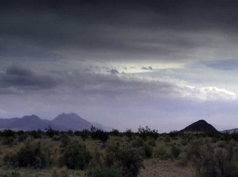 Time lapse storm clouds roil over a desert plain.