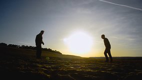 silhouettes of men playing football on beach in spring of, two guys playing football on sand in sun
