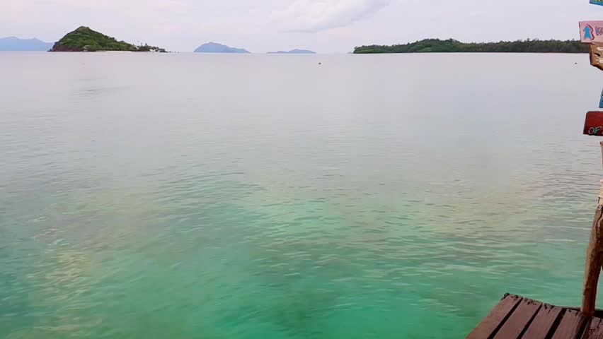 Man running and jumping off sea pier in the water, slow motion