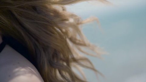 Wind blows girls blonde hair on tropical beach in Super slow motion