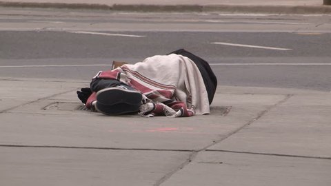 Toronto, Ontario, Canada March 2017 Homeless person lying on city street on cold winter day in Toronto