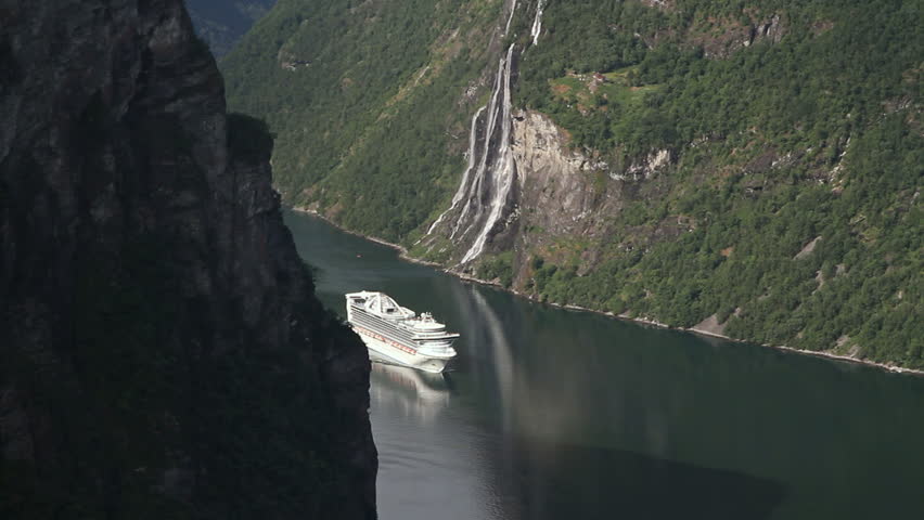 Cruise ship approaching the Geiranger Fjord in a beautiful scenery. To the right