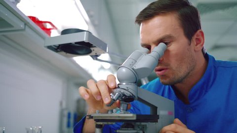 Scientist student working with microscope. Male scientist looking microscope. Close up of male chemist doing microscope research in lab. Man scientist looking at science microscope