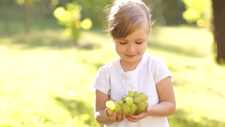 Smiling happy little girl with grapes