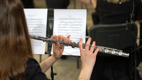 Female musician plays the flute. Flutist professionally playing the flute in the orchestra, classic music