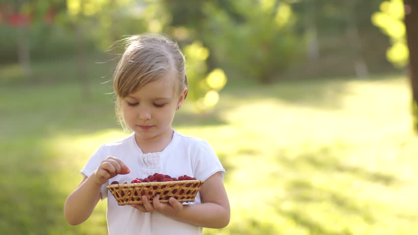 Girl eating raspberry and holding a basket