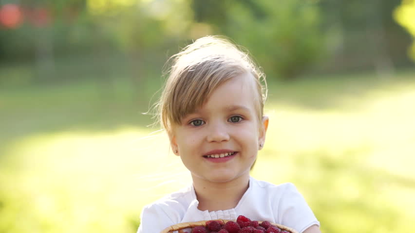Happy girl with basket of raspberry
