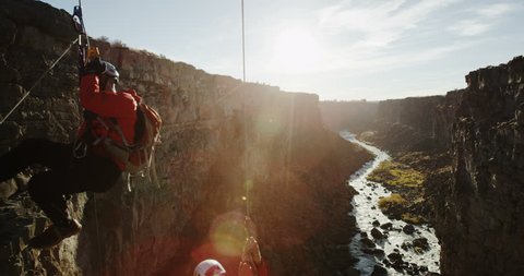 Two rock climbers ascending ropes while canyoneering sun setting in slow motion