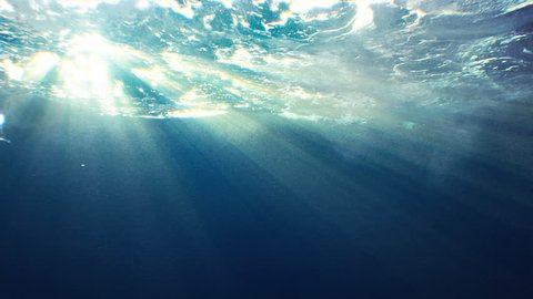 Beautiful underwater sea scene view with natural light rays, shining through the water's glittering and moving surface, caustics, bubbles, and foam, perfect for background and digital composition