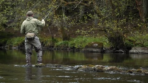 A fly fisherman hooking a trout in slow motion