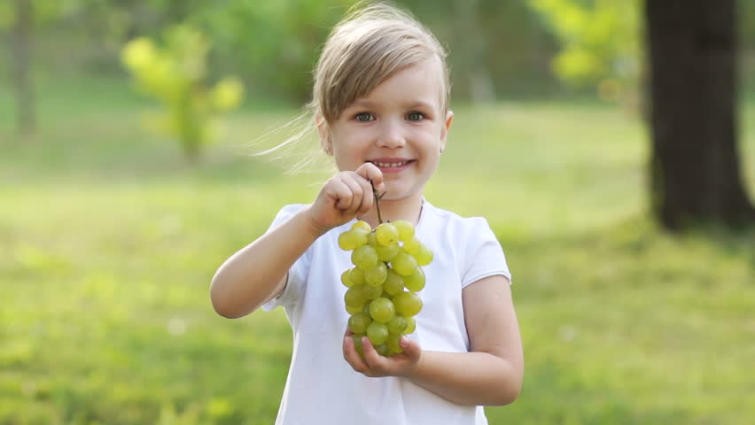 Girl with grapes. Thumbs up