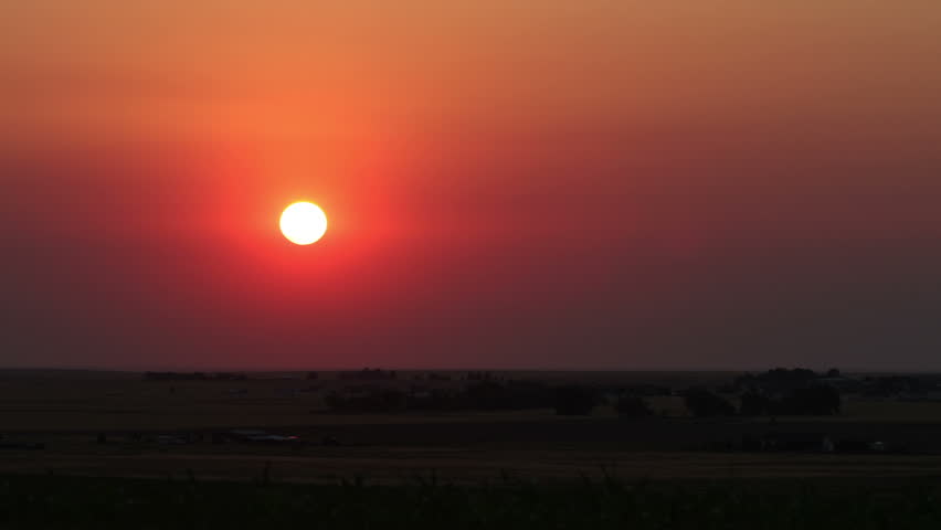 Sunrise on the plains, obscured by smoke from a brush fire in the summer heat