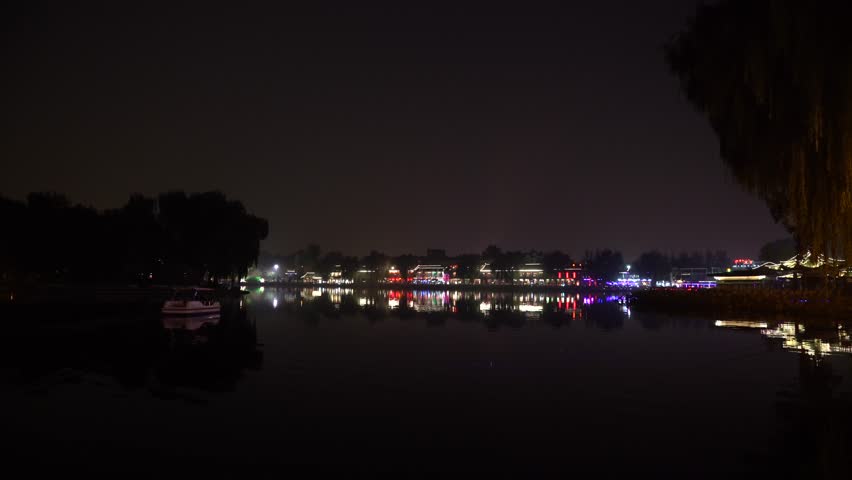 Night view of the city, city lights on the horizon. The boat sails on the lake. 4k