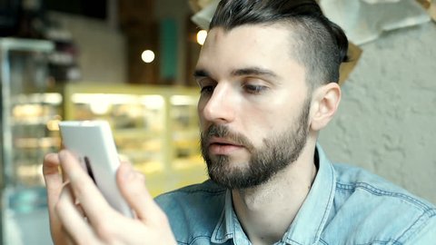 Handsome man looks happy while texting with someone on smartphone
