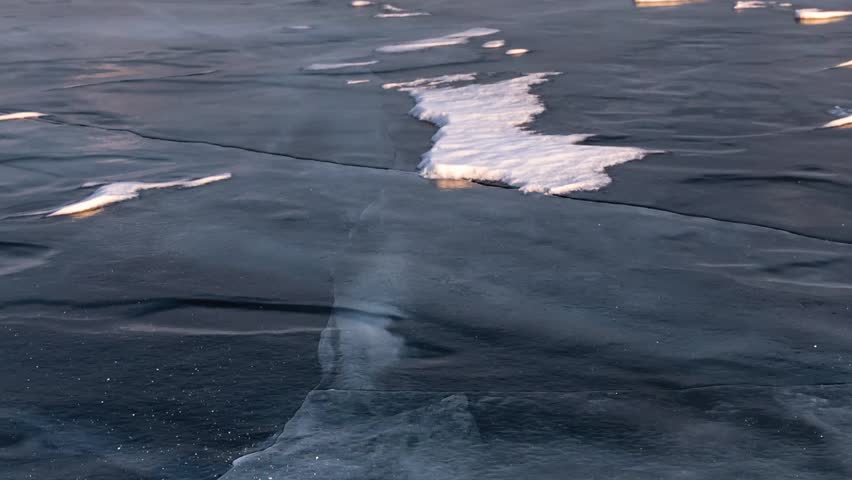 Time Lapse. The surface of the ice on the frozen lake in the rays of the setting sun. Baikal, Russia.