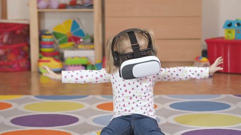 Girl wearing virtual reality goggles. Virtual reality game. The little girl with surprise and pleasure uses head-mounted display.