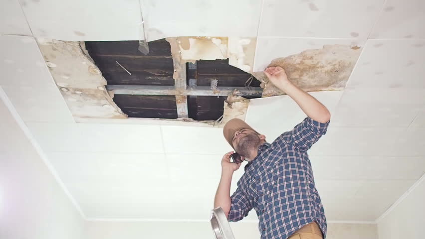 Young man call on the phone in the Service, and public utilities. Ceiling panels damaged huge hole in roof from rainwater leakage.Water damaged ceiling , Insurance case. Royalty-Free Stock Footage #24788660