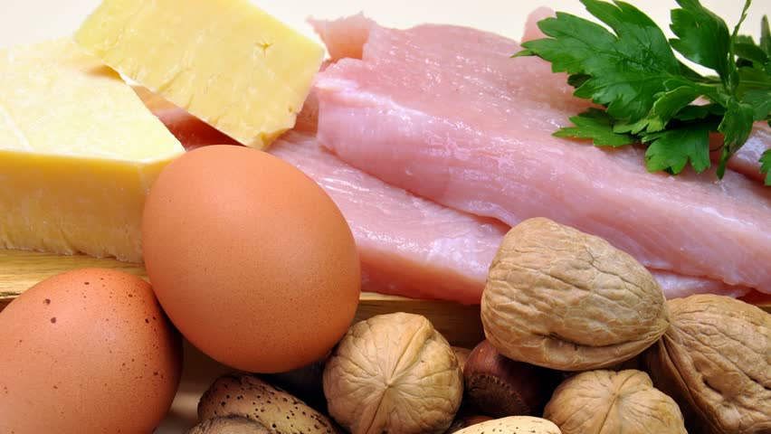 Closeup of sources of protein, dietary food group, including chicken, turkey fillets, cheese, eggs and nuts.