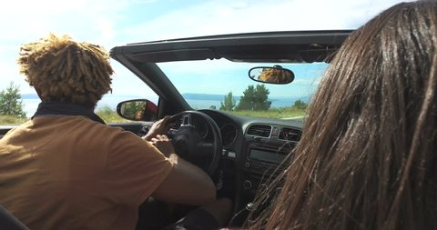 Handsome black man with dreadlocks turning on a highway in convertible car