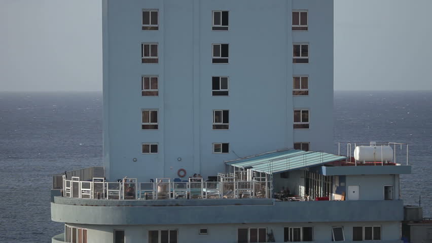 view of an old hotel and swimming pool with sea in background, havana, cuba