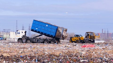 4K. Truck offloading waste into a huge landfill.