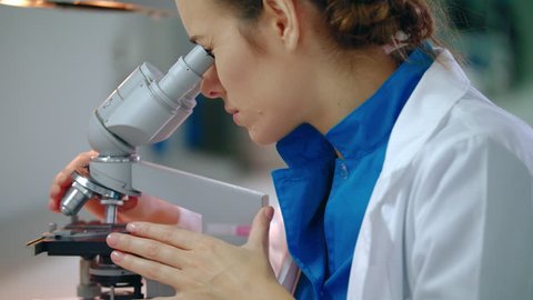 Chemistry scientist looking microscope. Close up of chemical scientist looking through microscope. Female chemist face looking microscope