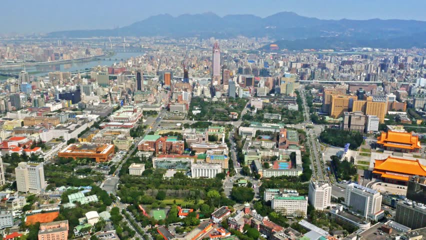 Aerial view of Taipei city, located in the north of the island of Taiwan. On the horizon you can appreciate the mountains. There is vegetation and parks around the buildings. 4K