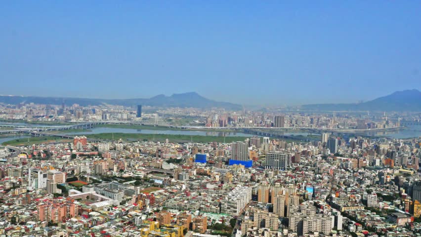 Aerial view of Taipei city, located in the north of the island of Taiwan. On the horizon you can appreciate the mountains. There is vegetation and parks around the buildings. 4K