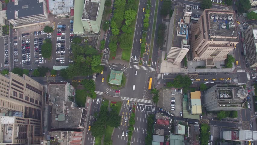 Flying above of a main road in Taipei city, located in the north of Taiwan. There is vegetation between the lanes of the road. There is a car traffic. 4K
